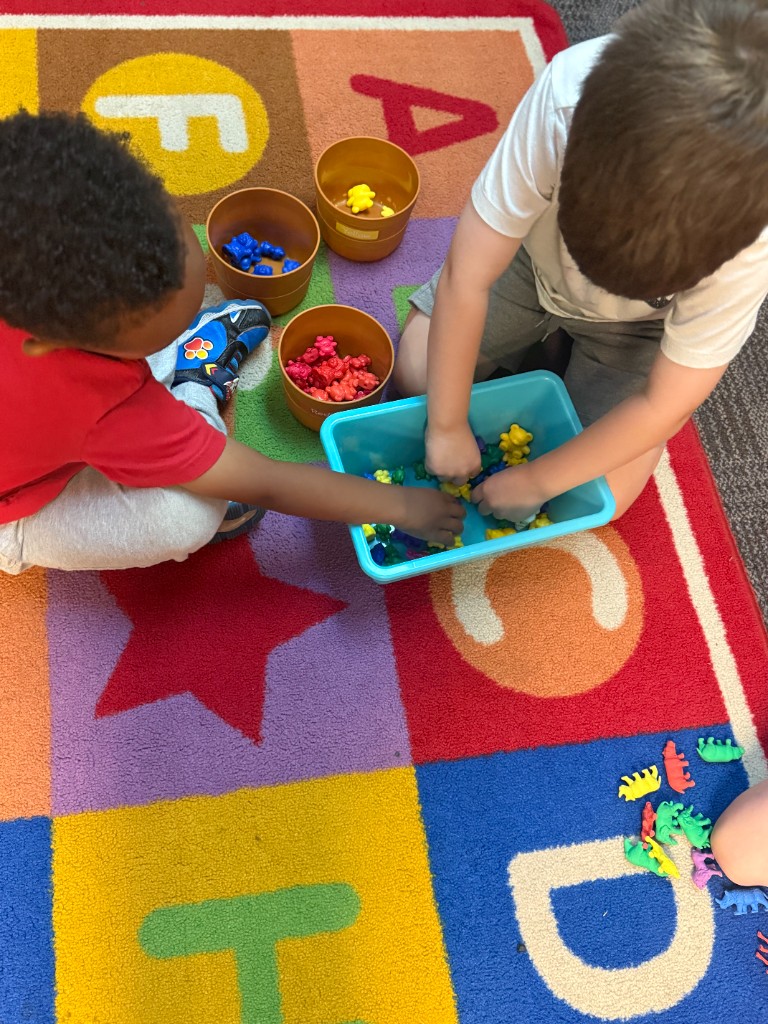 Two children sorting colorful animal counters on an alphabet rug