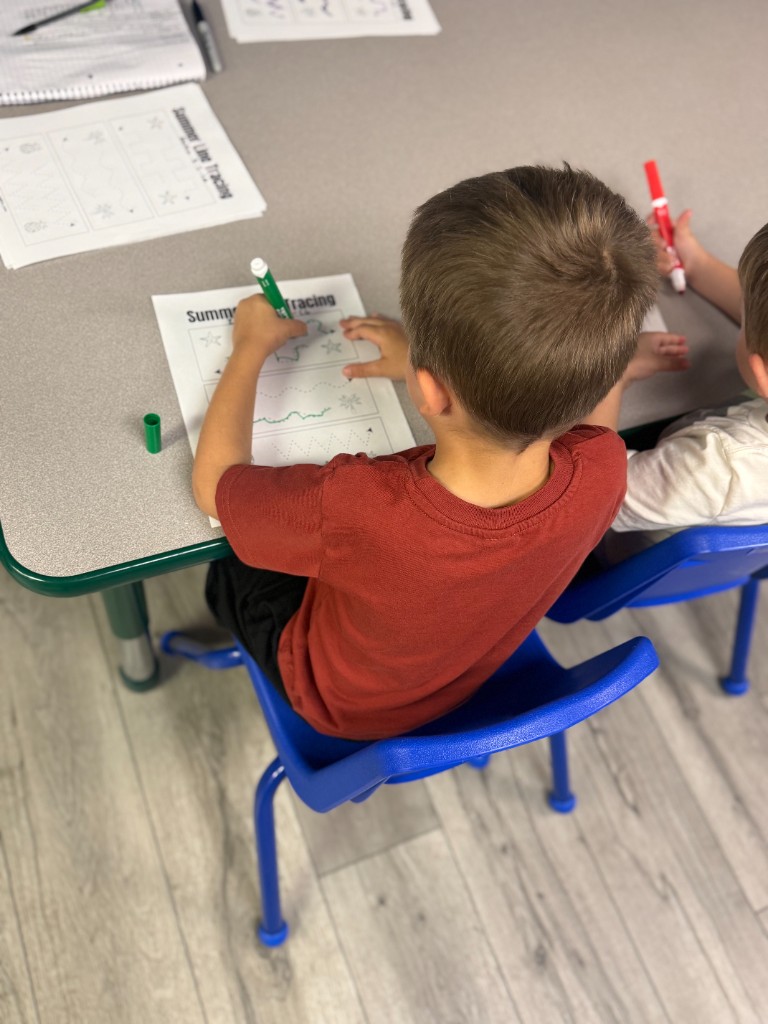 A child tracing lines with a marker during a table activity